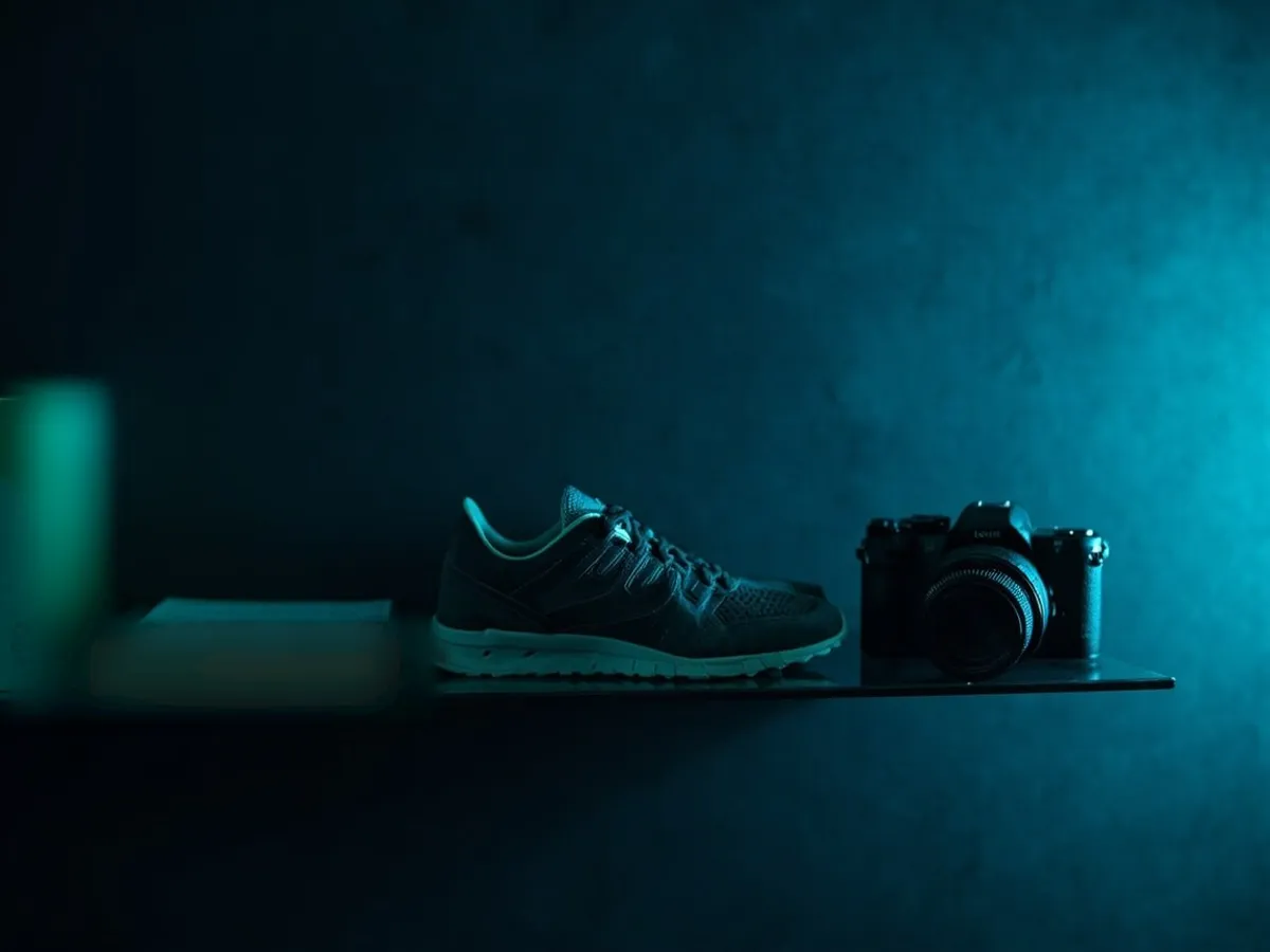 A cheap book, mid-priced shoes and a camera lined up on a shelf