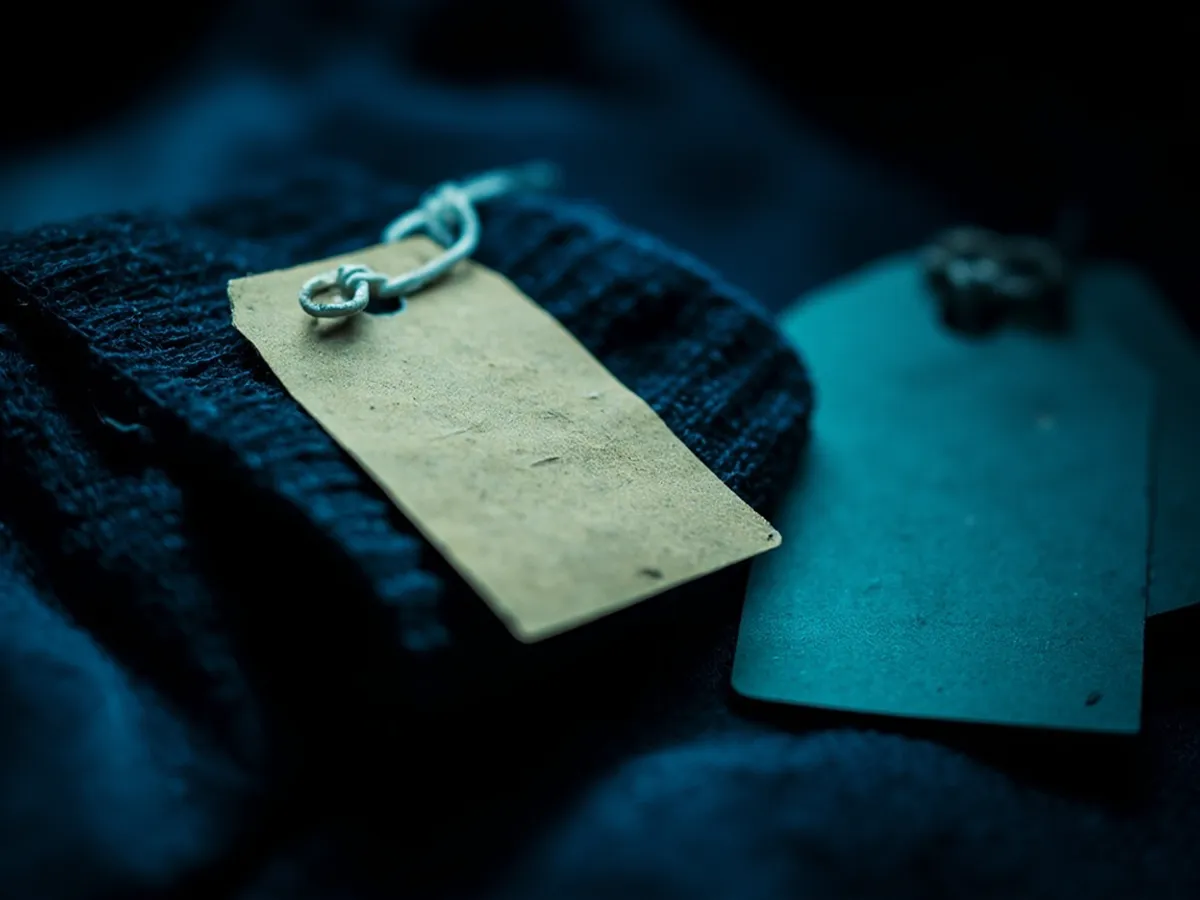 A tagged sweater cuff next to an identical untagged cuff with slight wear