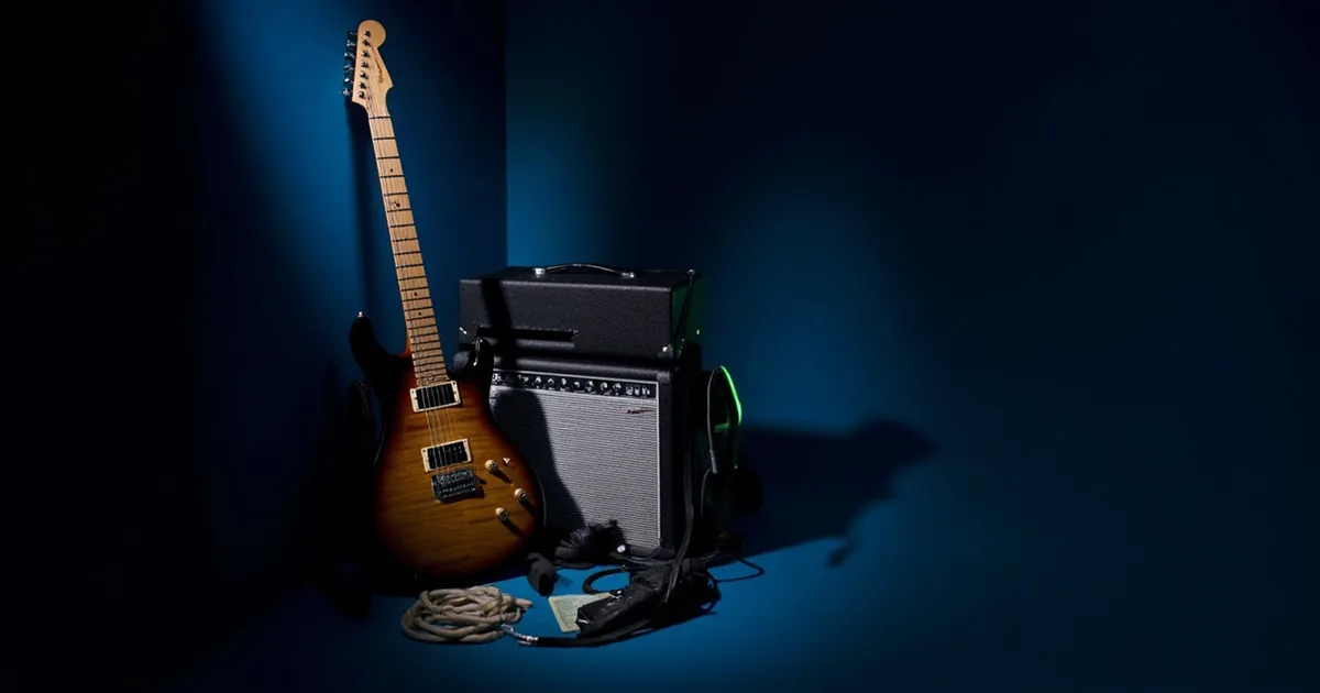 Electric guitar leaning on a combo amp with an open hard case behind them in a dim rehearsal room