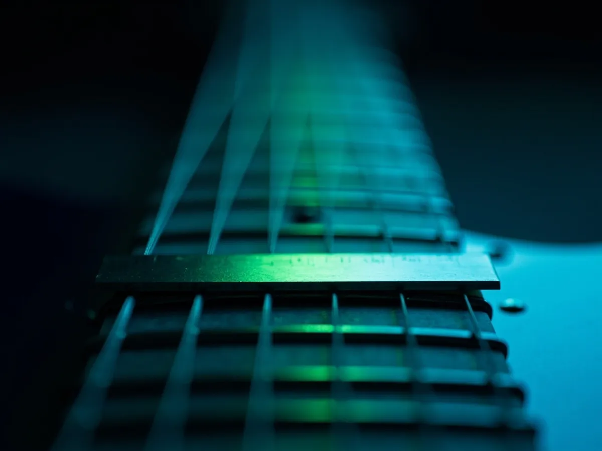 Close-up view along a guitar fretboard with a steel ruler resting across two frets
