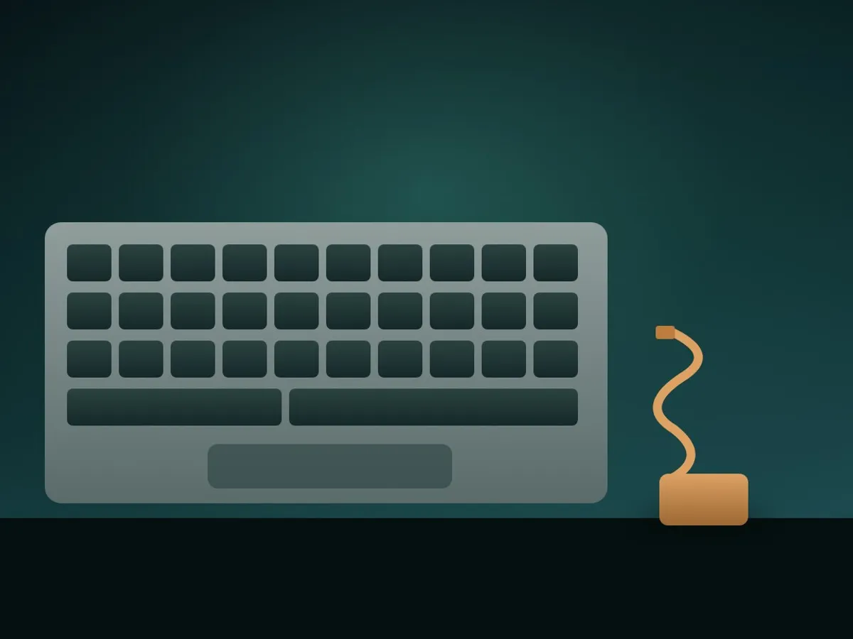 Close-up of a laptop keyboard with blank keys and a coiled charging cable