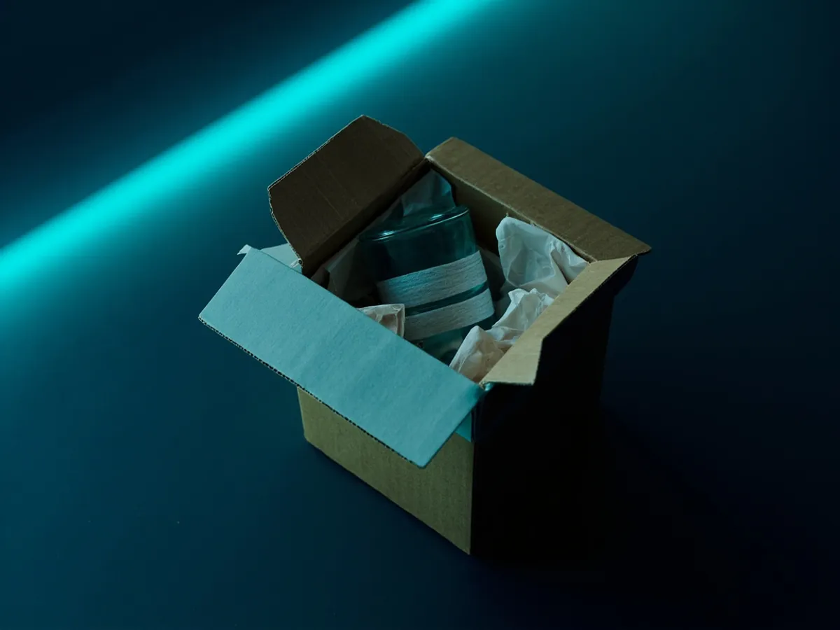 A small box nested inside a larger box with filler packed in the gap between them