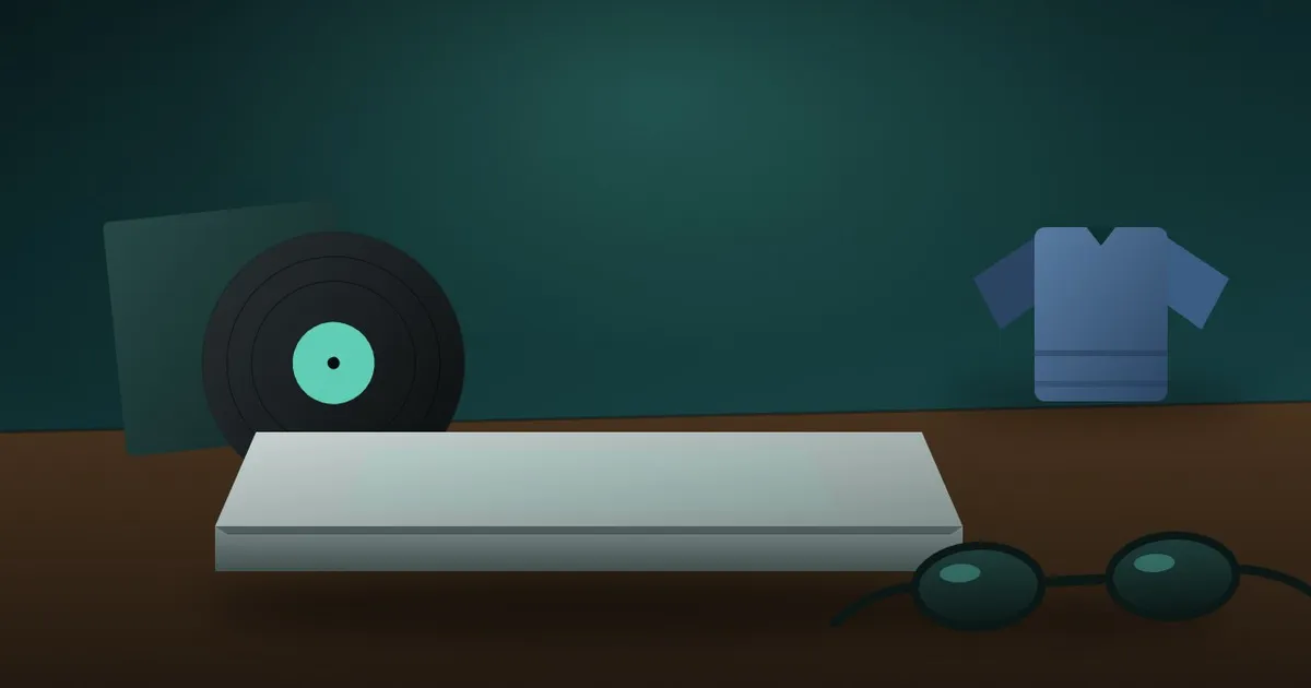 A closed laptop, a vinyl record, a folded jacket and sunglasses on a dark desk
