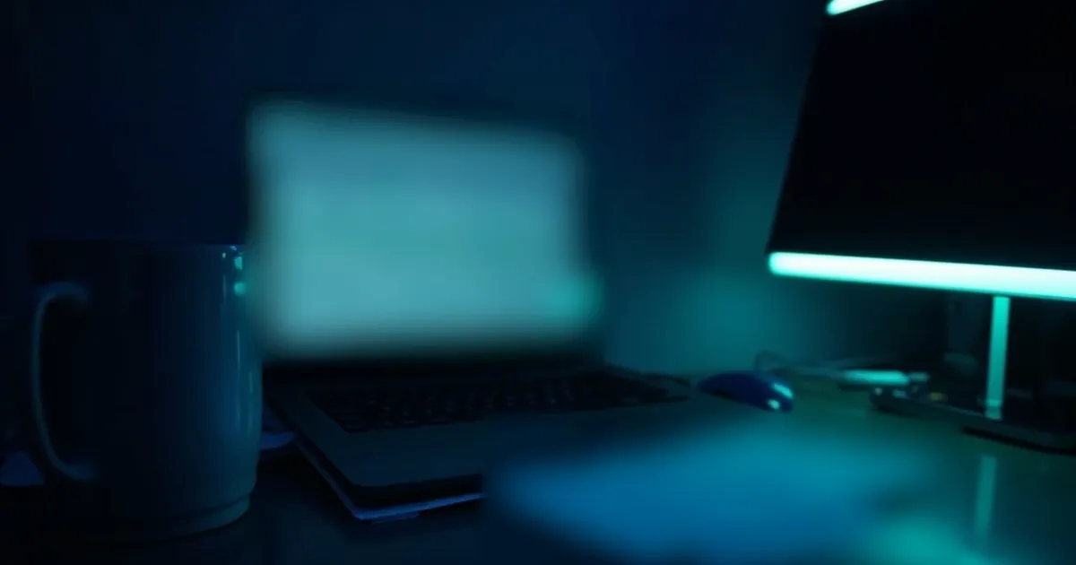 A laptop with a blank spreadsheet and shipping labels on a dark desk