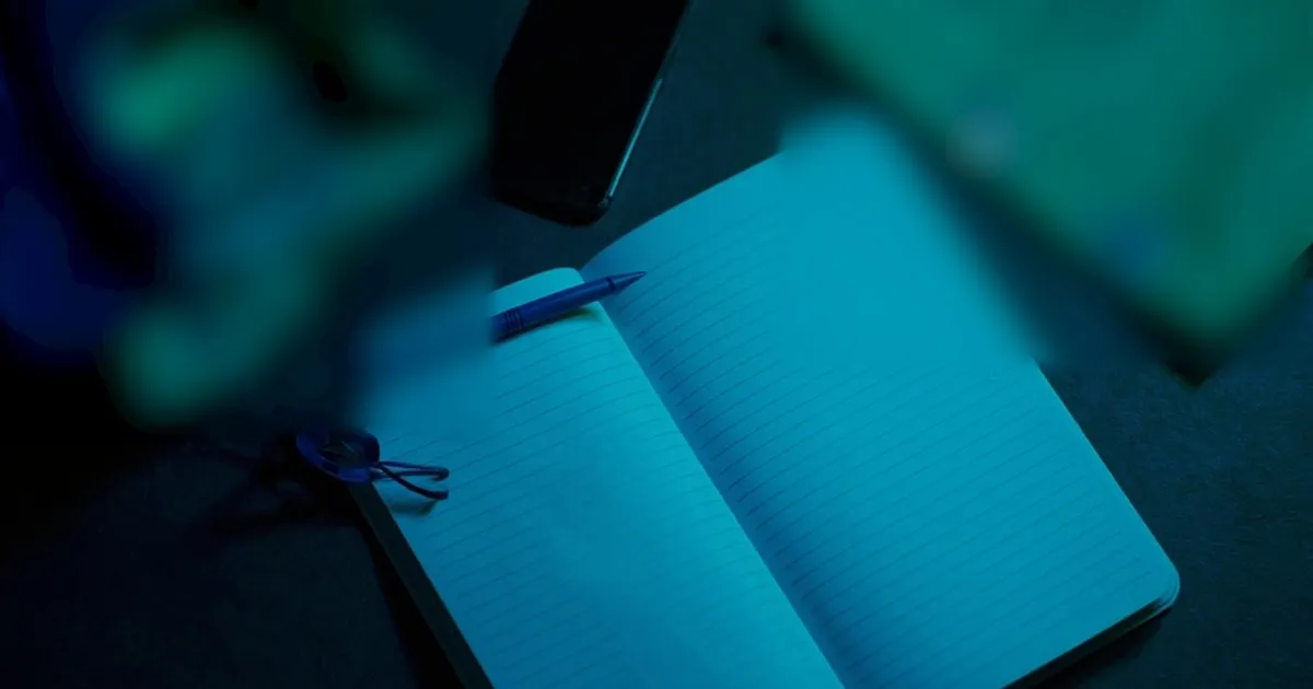 Open notebook with ruled columns, a pen and a thrift store bag with receipts clipped together on a desk