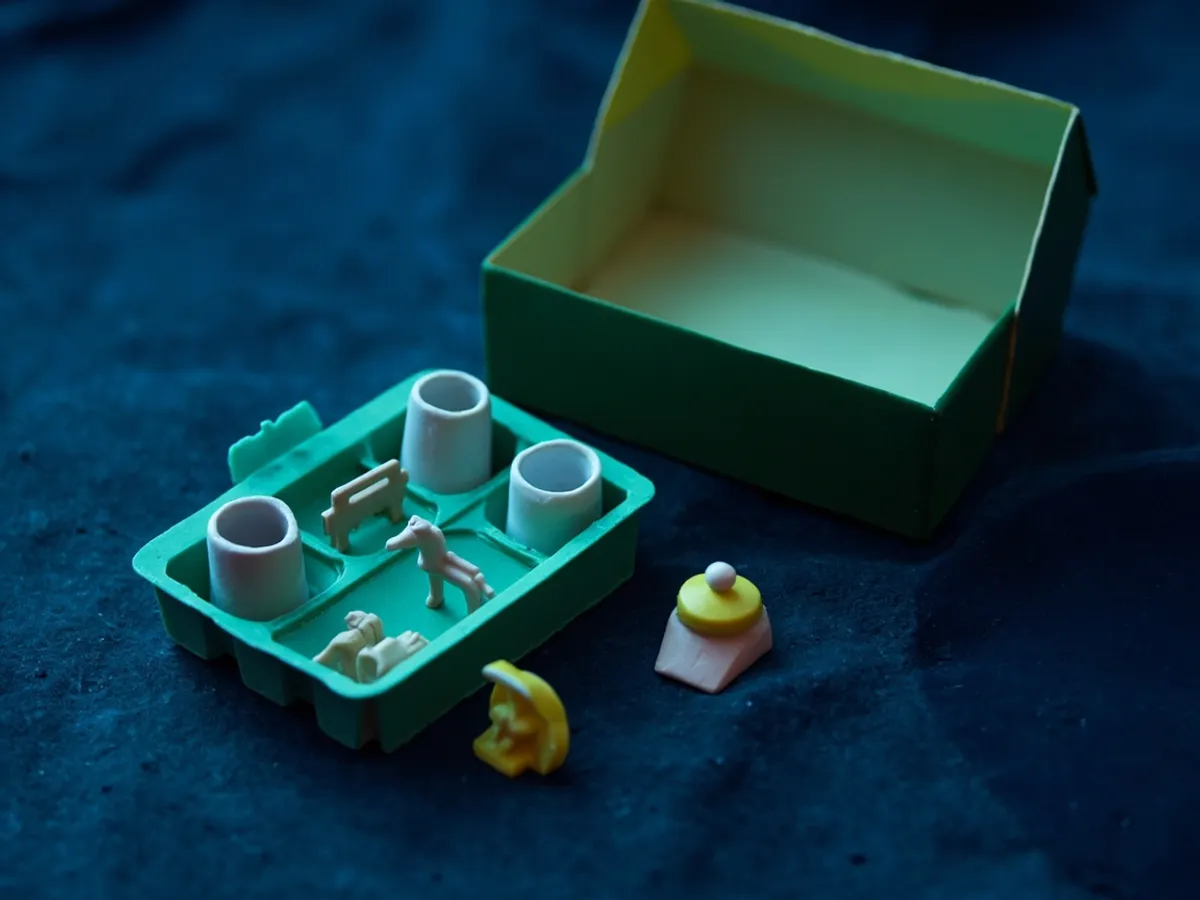 Small toy accessories sorted in a compartment tray beside an open play set box