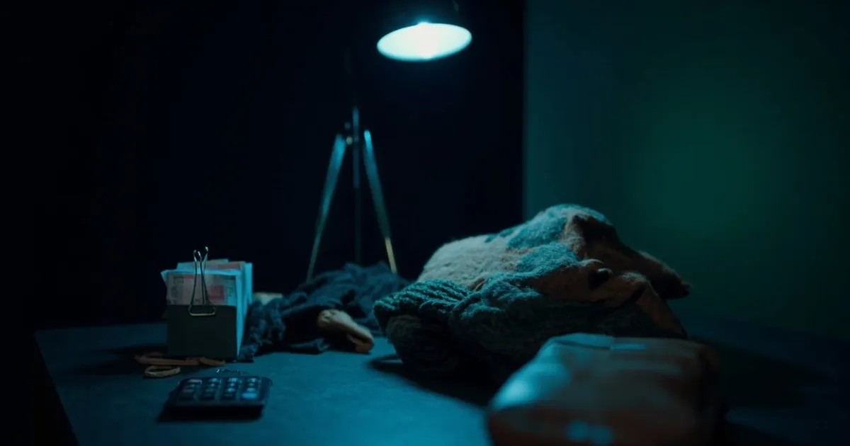 cash, a calculator and folded second-hand clothing arranged on a home office desk
